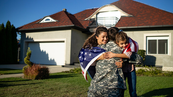 military family hugging in front of their home MRP